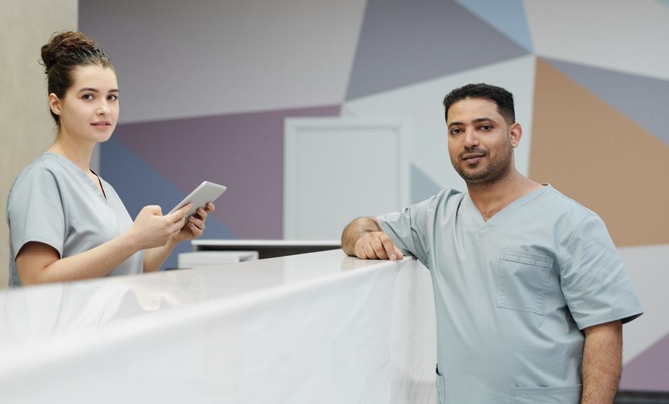 Two clinic staff members at the front desk, no paperwork in sight